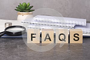 wooden blocks with text FAQS on black table