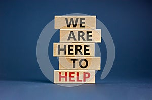 Wooden blocks with text `we are here to help`. Beautiful grey background, copy space. Business concept