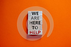 Wooden blocks with text `we are here to help`. Beautiful orange background, copy space. Business concept