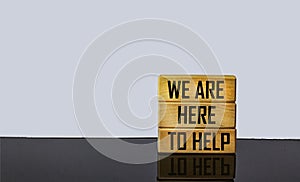 Wooden blocks with text We are here to help. Beautiful white background, copy space. Business concept
