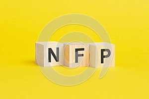 wooden blocks with text NFP on yellow background. business concept photo