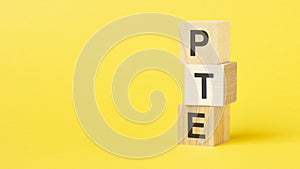 wooden blocks with the text PTE - short for Pearson Tests of English on a bright yellow background