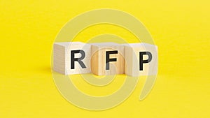 wooden blocks with text RFP on yellow background. business concept