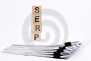 wooden blocks with text SERP on white table, stack white paper on background