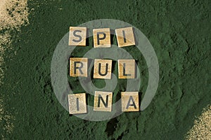 Wooden blocks with text SPIRULINA chlorella on background of algae superfood powder. Healthy benefits supplement and