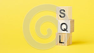 wooden blocks with the text sql - short for structured query language on a bright yellow background