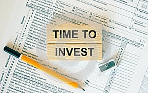 Wooden blocks with text Time To Invest on financial docs