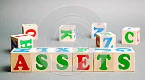 Wooden blocks with the word Assets and randomly scattered cubes. Resource owned by the business. Financial accounting. Money and
