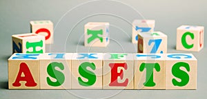 Wooden blocks with the word Assets and randomly scattered cubes. Resource owned by the business. Financial accounting. Money and