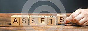 Wooden blocks with the word Assets and randomly scattered cubes. Resource owned by the business. Financial accounting. Money and