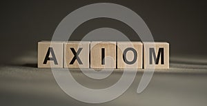 A wooden blocks with the word AXIOM written on it on a gray background