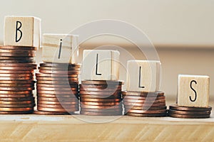 Wooden blocks with the word bills and pile of coins, money climbing stairs Payment of taxes and of debt to the state. Concept of