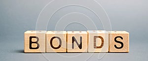 Wooden blocks with the word Bonds. A bond is a security that indicates that the investor has provided a loan to the issuer. photo