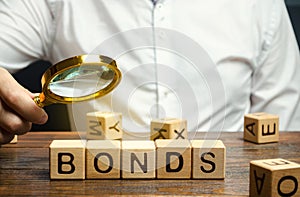 Wooden blocks with the word Bonds and businessman. A bond is a security that indicates that the investor has provided a loan to