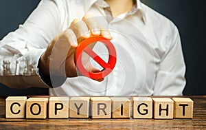 Wooden blocks with the word Copyright and the prohibition sign in the hands of a businessman. Patenting. Copyright protection.