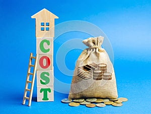 Wooden blocks with the word Cost, a ladder and a wooden house with a bag. Real estate pricing concept. Expensive prices for the