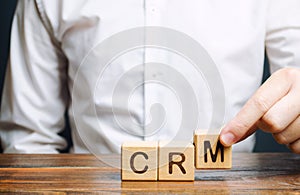 Wooden blocks with the word CRM Customer Relationship Management and businessman. Automation strategies for interacting with