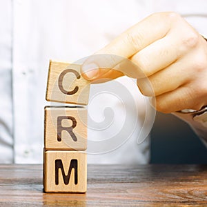 Wooden blocks with the word CRM Customer Relationship Management and businessman. Automation strategies for interacting with