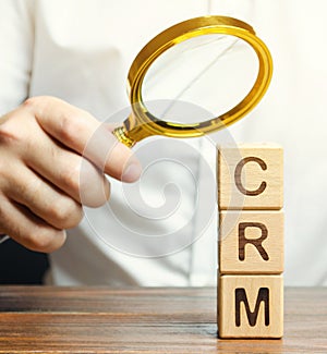 Wooden blocks with the word CRM Customer Relationship Management and businessman. Automation strategies for interacting with