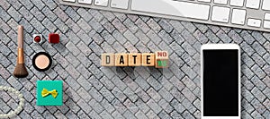 Wooden blocks with the word DATE and the option between NO and YES with smartphone, keyboard and cosmetica photo