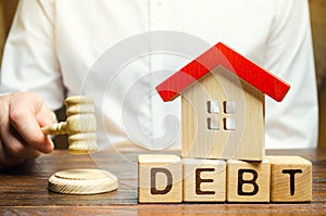 Wooden blocks with the word Debt and a miniature house with a judge`s hammer. Confiscation of property for failure to pay the deb