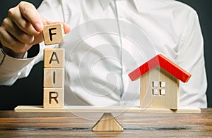 Wooden blocks with the word Fair and a wooden house. Fair value of real estate and housing. Property valuation. Home appraisal.