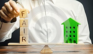 Wooden blocks with the word Fair and a wooden house. Fair value of real estate and housing. Property valuation. Home appraisal.