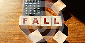 Wooden blocks with the word Fall and calculator. Unsuccessful business and bankruptcy. Profit decline. Loss of investment.