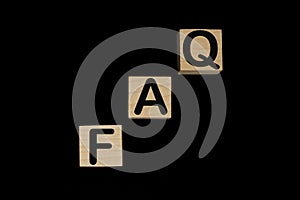 Wooden blocks with word FAQ on black baclground. Frequently asked question concept