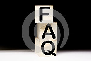 Wooden blocks with word FAQ on black baclground. Frequently asked question concept