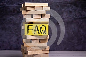Wooden blocks with word FAQ on wooden background. Frequently asked question concept