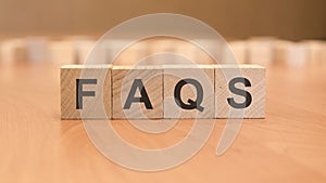 wooden blocks with word FAQS on yellow background. frequently asked question concept