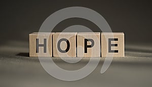 A wooden blocks with the word HOPE written on  it on a gray background