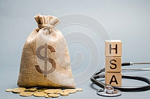 Wooden blocks with the word HSA and money bag with stethoscope. Health savings account. Health care. Health insurance. Investments