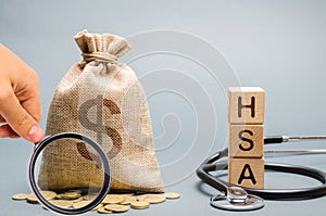 Wooden blocks with the word HSA and money bag with stethoscope. Health savings account. Health care. Health insurance. Investments