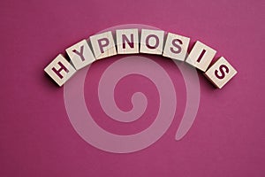 Wooden blocks with word HYPNOSIS on magenta background photo