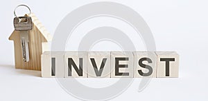 Wooden blocks with the word INVEST , house. Real estate market