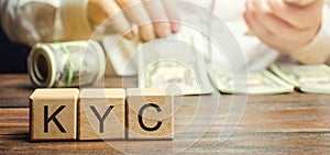 Wooden blocks with the word KYC - Know Your Customer / Client. Verify the identity, suitability and risks involved with photo