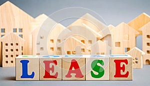 Wooden blocks with the word Lease and miniature houses. Investment activity for the acquisition of property with the right to