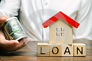 Wooden blocks with the word Loan, house and money in the hands of a businessman. The concept of buying an apartment or house in