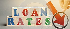 Wooden blocks with the word Loan rates and arrow down. The concept of low mortgage rates. Real estate market. Housing. Credit.