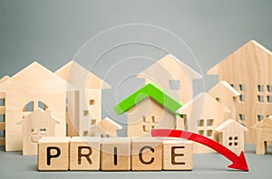 Wooden blocks with the word Price, down arrow and miniature houses. Reduced housing prices. The fall and crisis of the real estate