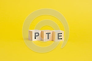 wooden blocks with word PTE on yellow paper. pearson tests of english concept