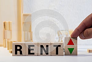 Wooden blocks with the word Rent, house and up arrow. The concept of the high cost of rent for an apartment or home