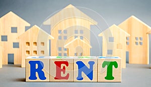 Wooden blocks with the word Rent and wooden houses. The concept of renting housing and real estate. The cost of a rented home or