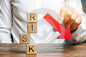 Wooden blocks with the word Risk and a down arrow. Reduce financial risk for investment and capital. Protection of investment