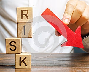 Wooden blocks with the word Risk and a down arrow. Reduce financial risk for investment and capital. Protection of investment