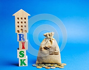 Wooden blocks with the word Risk and a miniature house with a money bag. Real estate investment risk. Risky investments. Loss of