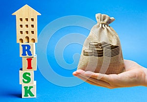 Wooden blocks with the word Risk and a miniature house with money bag. Real estate investment risks. Risky investments. Loss of