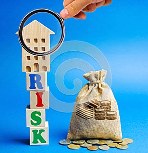 Wooden blocks with the word Risk and a miniature house with a money bag. Real estate investment risk. Risky investments. Loss of